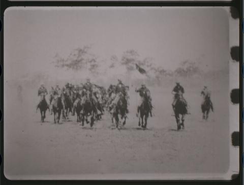 Black and white film depicting a group of Rough Riders on horseback.