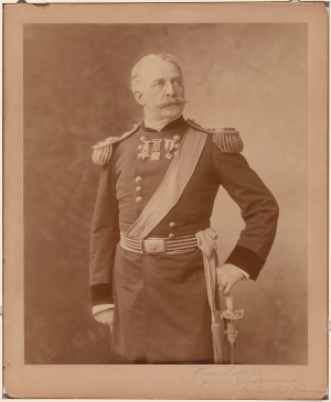 Sepia tinted photograph of a man in full military dress with epaulets, sash and sword.