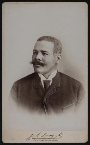 Bust length photo of a man in a dark suit with a moustache