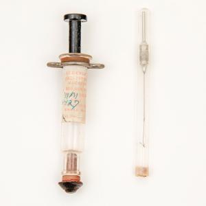Old syringe with medical label attached.