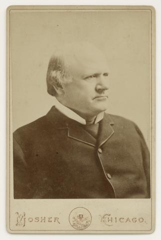 Bust-length carte de visite of a man in a dark high-buttoned suit.